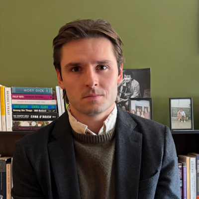 PhD candidate Lincoln Hirn sitting in front of a bookcase