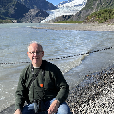 Adjunct Professor Thomas Maulucci in front of a sunny mountain and lake